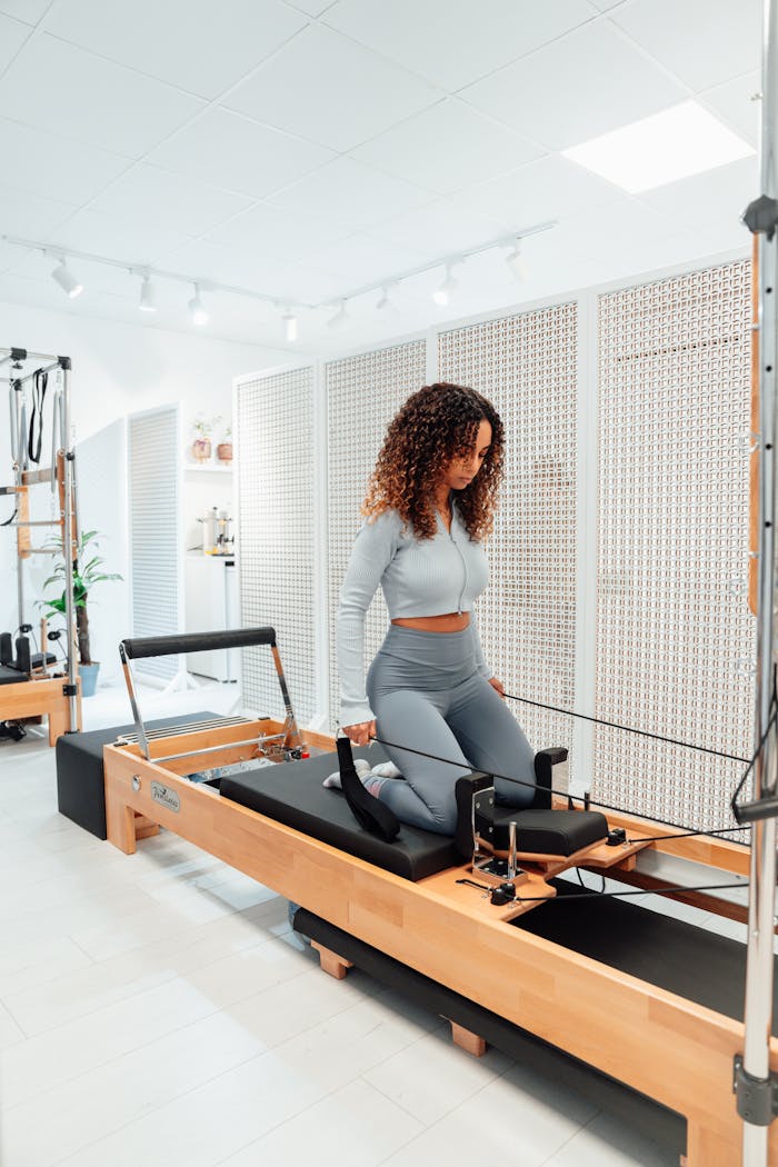 Woman in a Gray Tracksuit on a Pilates Tower